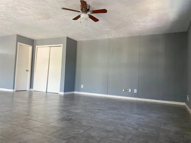 a view of an empty room with window and a ceiling fan