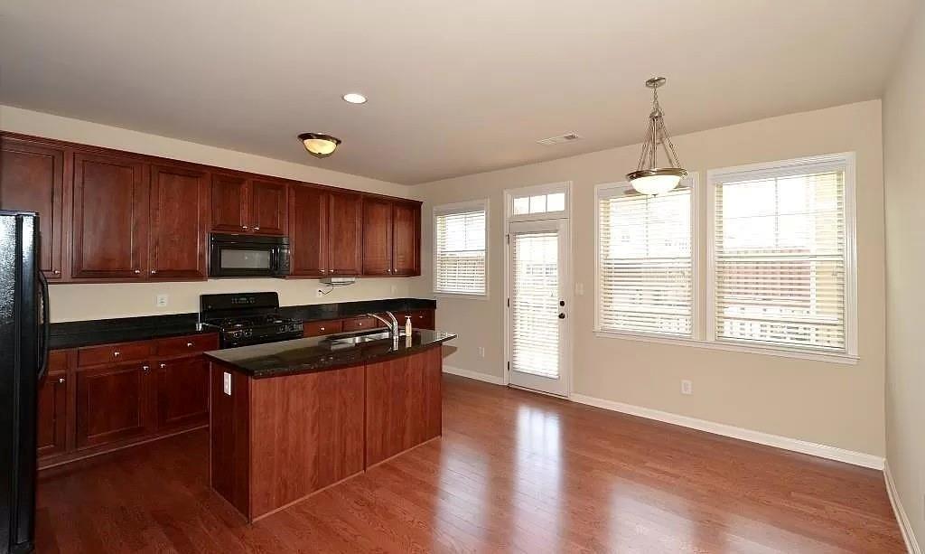 4411 Village Field Place Suwanee, GA 30024 - Photo 3 of 9 a kitchen with wooden floors and wooden cabinets