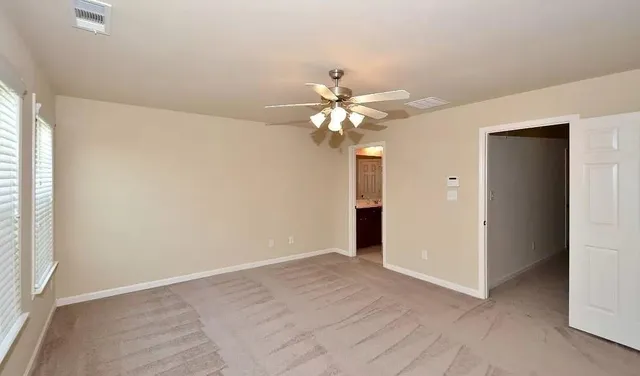 an empty room with a chandelier fan and windows