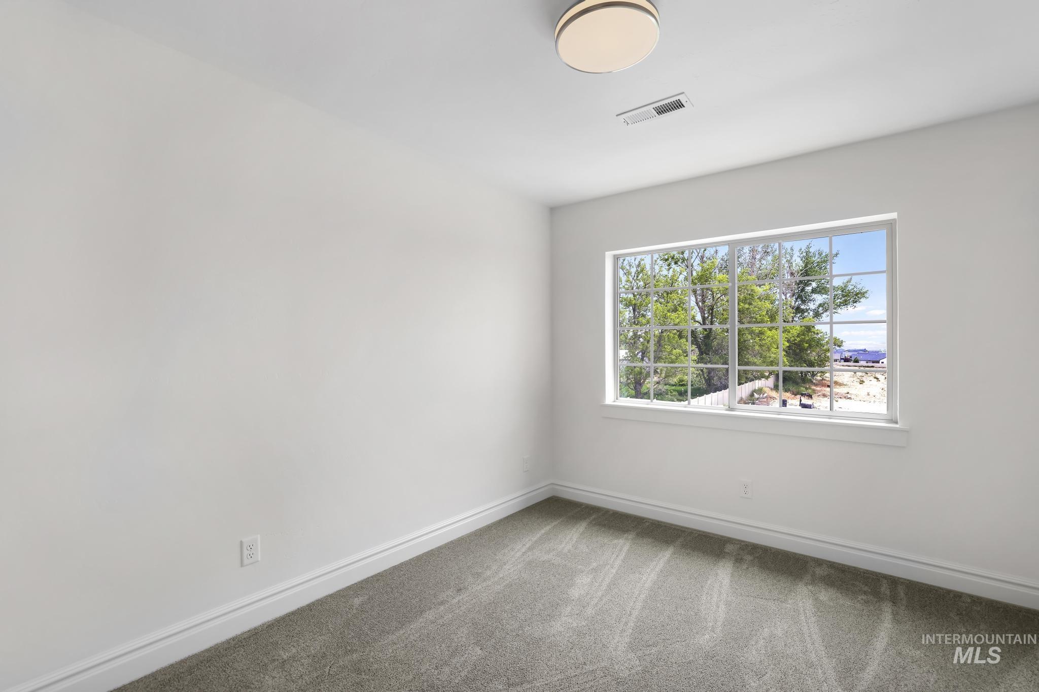 866 Quartz Road Kimberly, ID 83341 - Photo 32 of 48 Bright room featuring a large window with grid pattern, neutral carpet flooring, white walls, and a contemporary flush-mount ceiling light