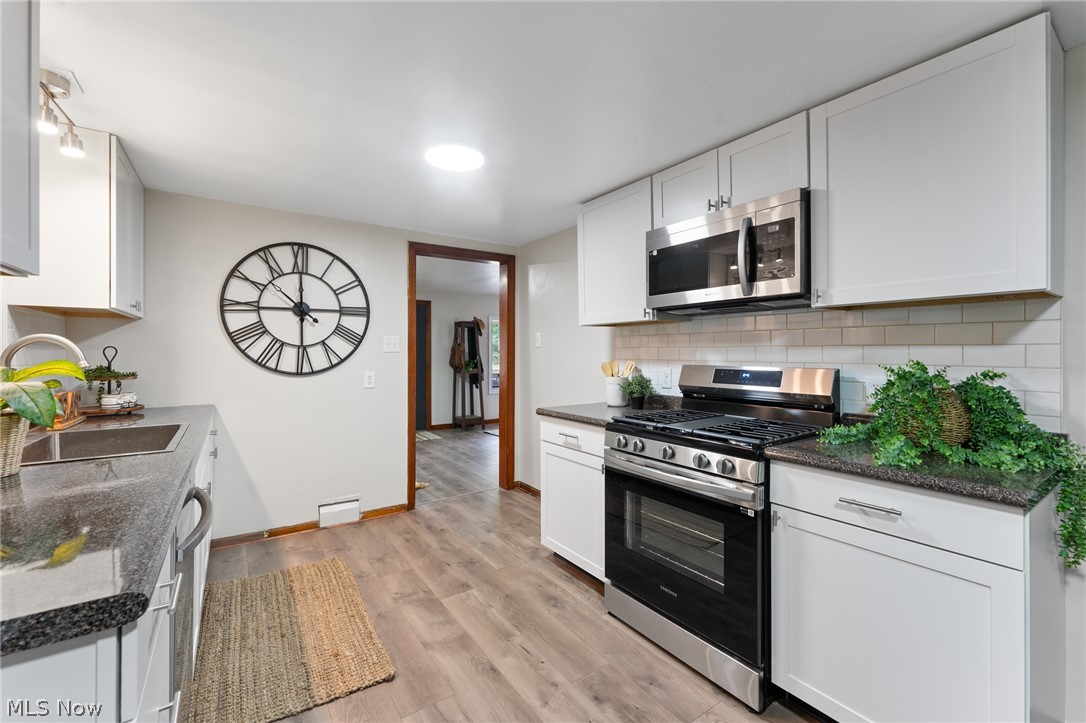 3568 McCartney Road Youngstown, OH 44505 - Photo 12 of 29 Kitchen with appliances with stainless steel finishes, white cabinetry, backsplash, and light wood-type flooring