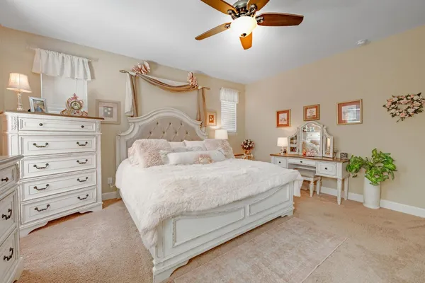 a spacious bedroom with a bed a chandelier and a potted plant