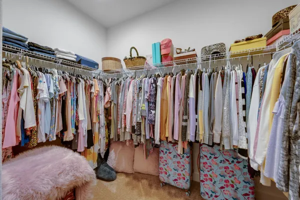 a view of walk in closet with clothes and shoes