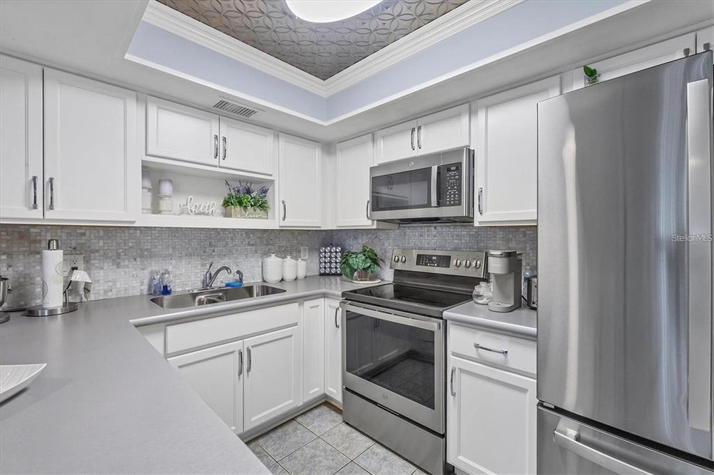 460 Base Avenue East, Unit 113 Venice, FL 34285 - Photo 17 of 25 a kitchen with stainless steel appliances granite countertop a refrigerator stove a sink and white cabinets