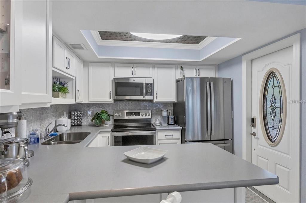 460 Base Avenue East, Unit 113 Venice, FL 34285 - Photo 18 of 25 a kitchen with stainless steel appliances granite countertop a refrigerator a stove top oven a sink and dishwasher