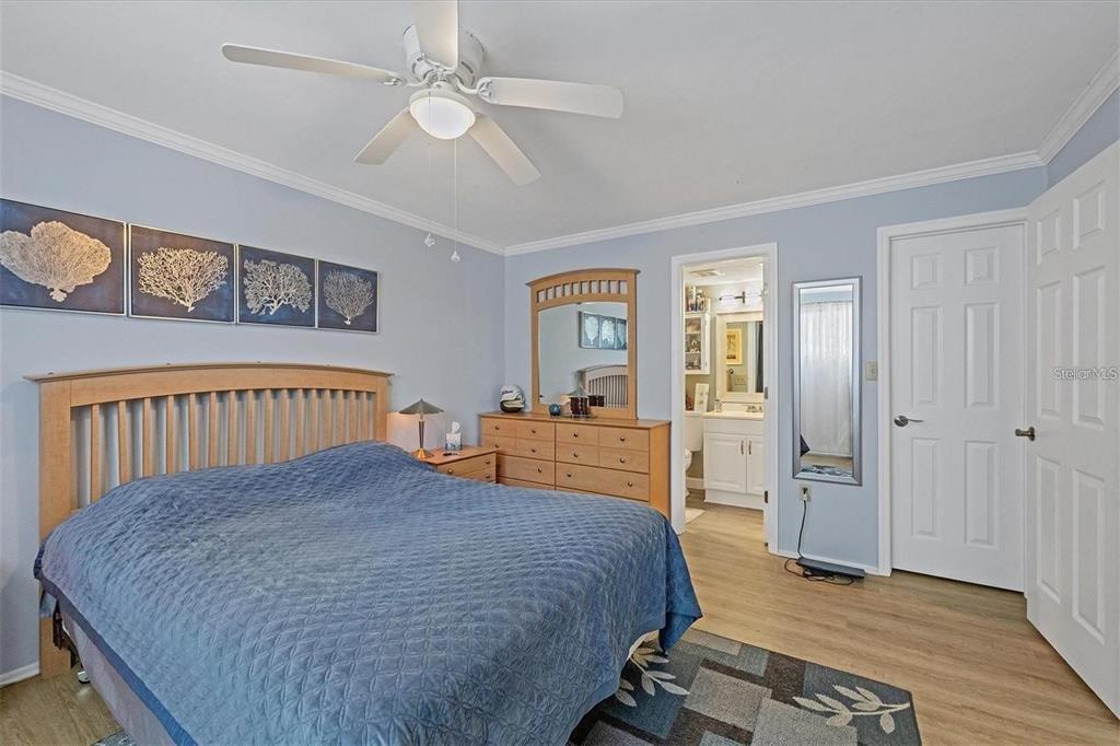 460 Base Avenue East, Unit 113 Venice, FL 34285 - Photo 10 of 25 a bedroom with a large bed and a chandelier