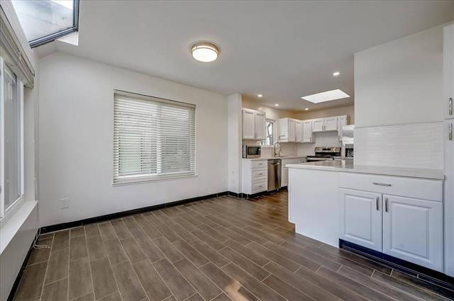 262 Beachview Avenue, Unit 5 Pacifica, CA 94044 - Photo 10 of 23 a kitchen with white cabinets and wooden floor