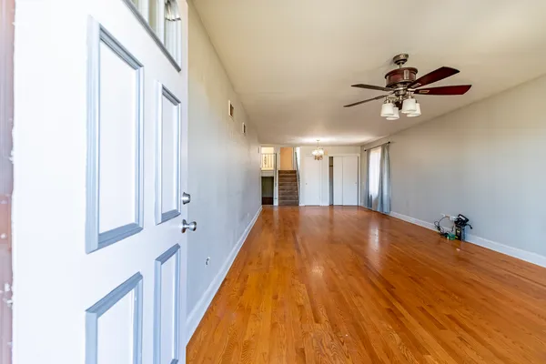 a view of a room with wooden floor and a ceiling fan