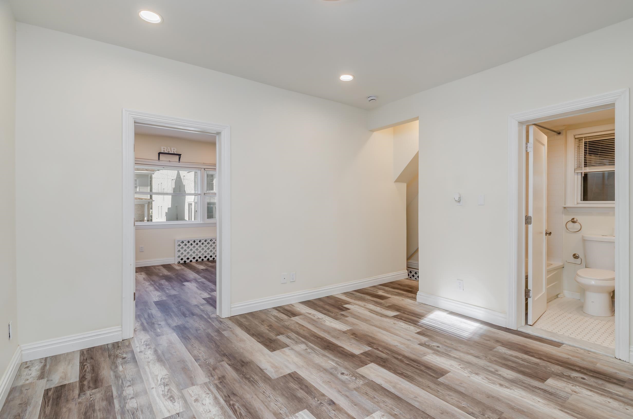 232 Pearsall Avenue, Unit 1 Jersey City, NJ 07305 - Photo 9 of 20 an empty room with wooden floor and a bathroom