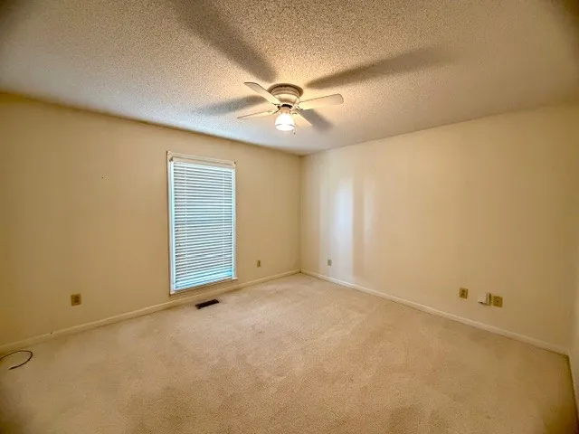 an empty room with windows and fan