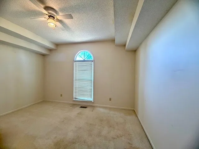 an empty room with windows and fan