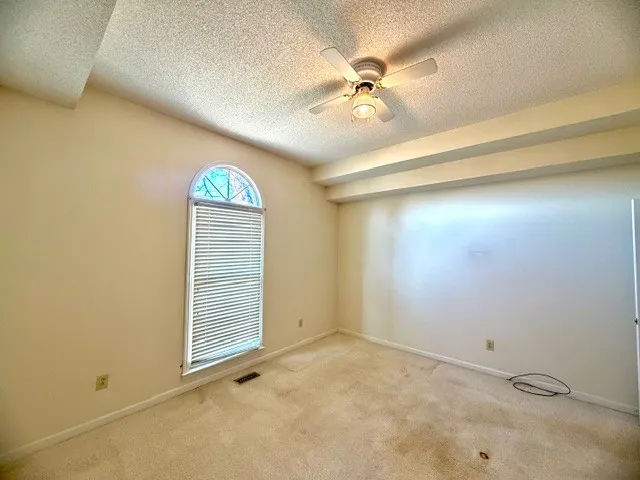 an empty room with a chandelier fan and windows