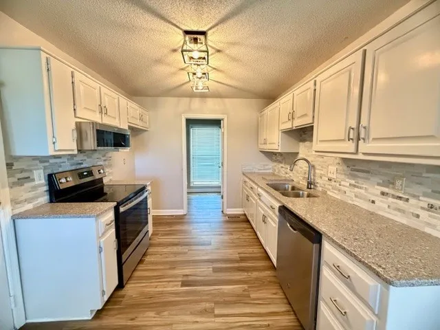 a large kitchen with stainless steel appliances granite countertop a sink stove and refrigerator