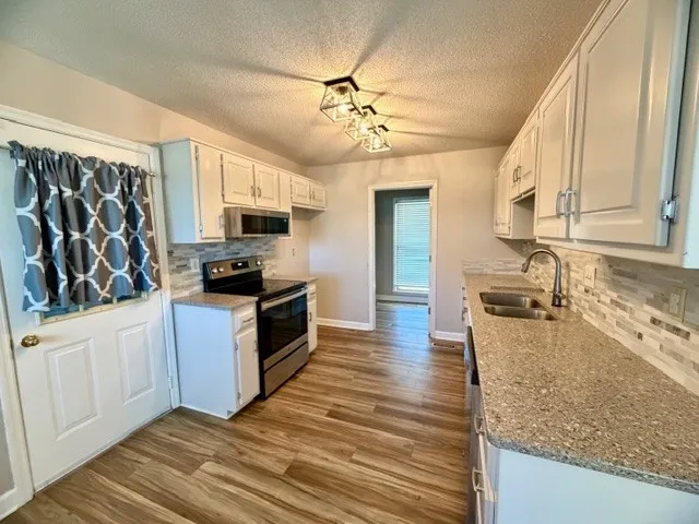 a kitchen with stainless steel appliances granite countertop a sink dishwasher stove and refrigerator with wooden floor