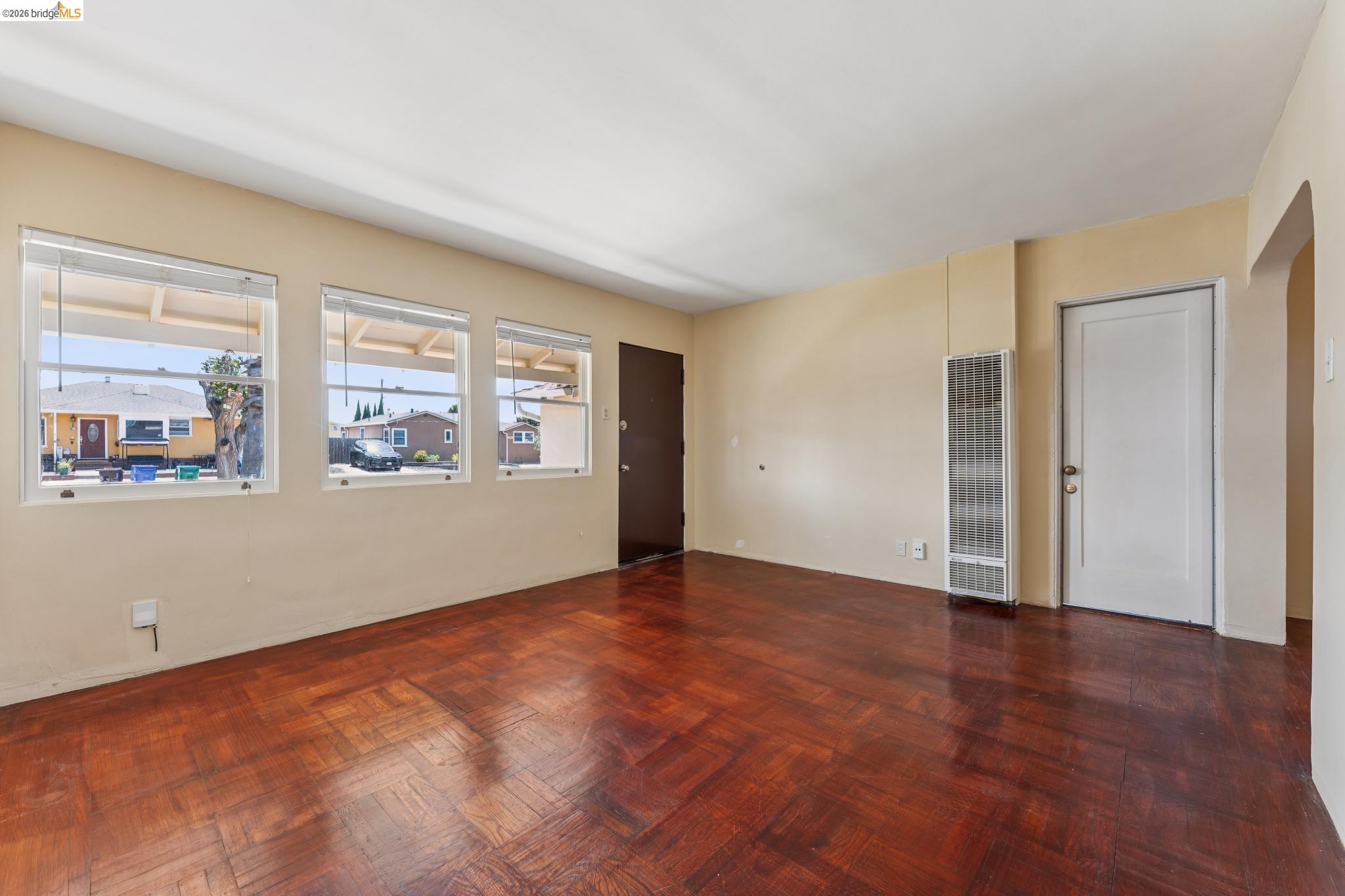 2879 Rheem Avenue Richmond, CA 94804 - Photo 10 of 45 Living space featuring herringbone wood-finish flooring, multiple windows, a wall-mounted heater, and a white paneled door