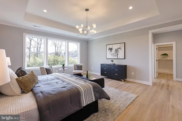 a spacious bedroom with a bed a chandelier and a window