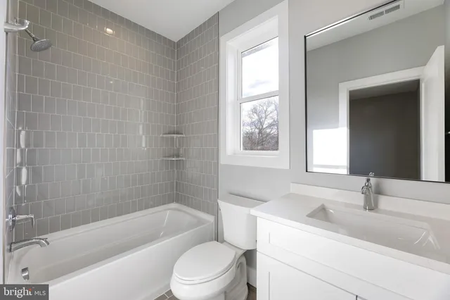 a bathroom with a granite countertop sink a toilet and bathtub