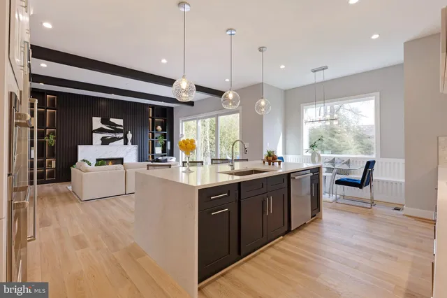 a living room with stainless steel appliances granite countertop furniture wooden floor and a view of kitchen