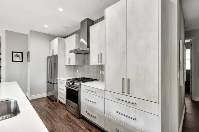 a kitchen with stainless steel appliances granite countertop a refrigerator a stove and a sink with wooden floor