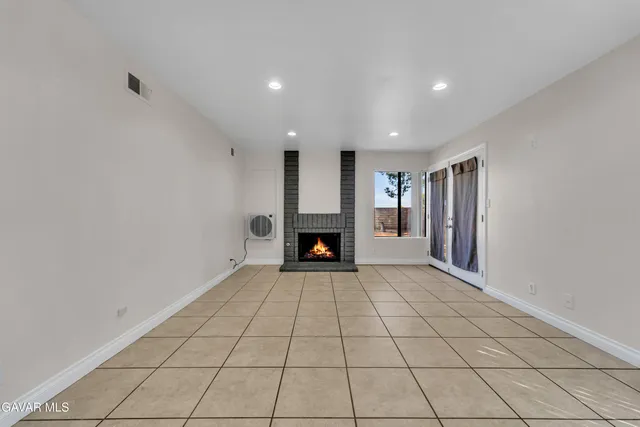 a view of an empty room with a fireplace and a window