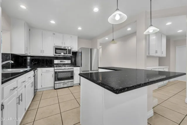 a kitchen with kitchen island granite countertop a sink a counter top space appliances and cabinets