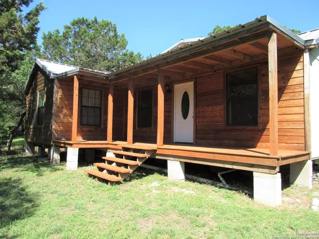 a backyard of a house with wooden fence and large trees