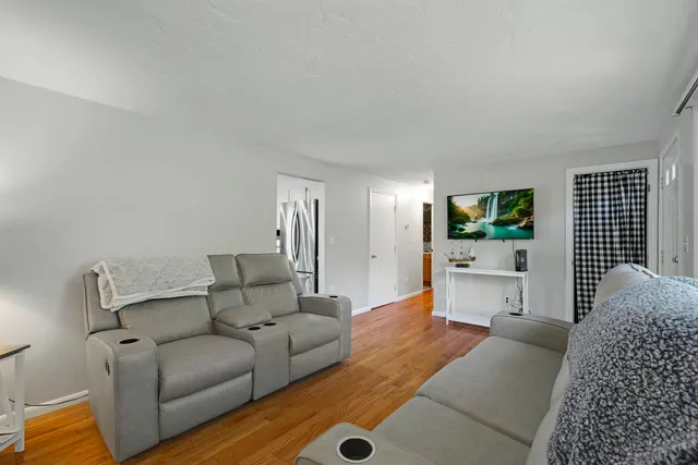 a living room with furniture a flat screen tv and a window