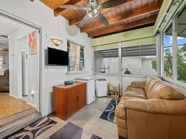 a living room with furniture a flat screen tv and a floor to ceiling window