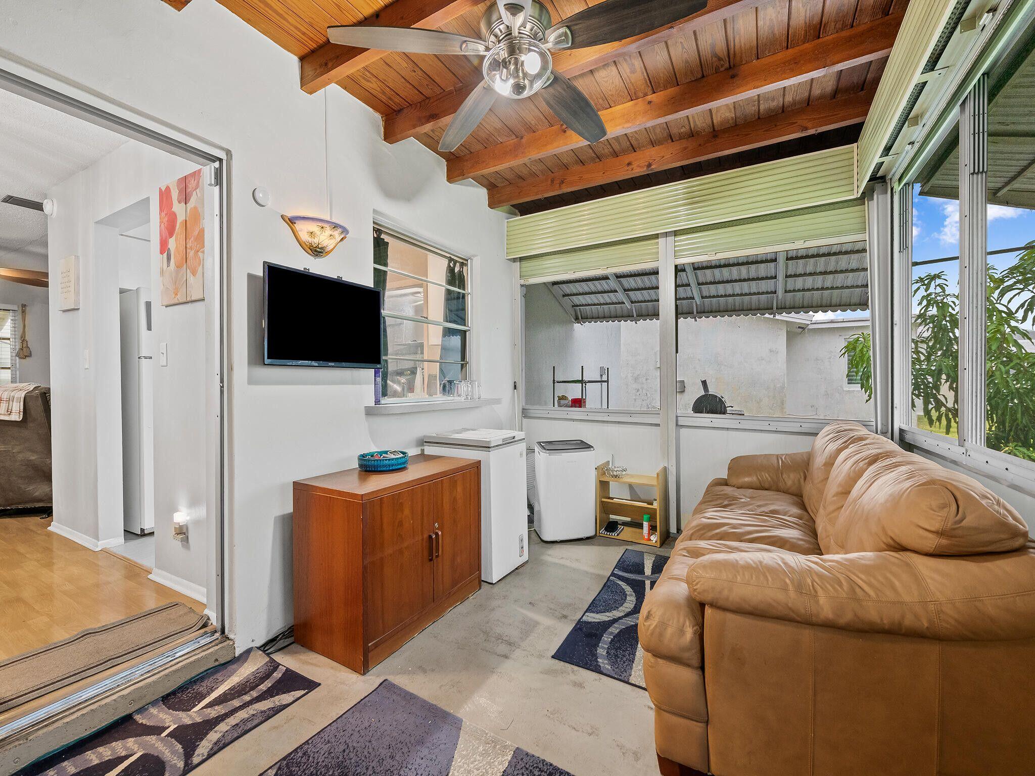 210 Northwest 25th Court Pompano Beach, FL 33064 - Photo 11 of 17 a living room with furniture a flat screen tv and a floor to ceiling window