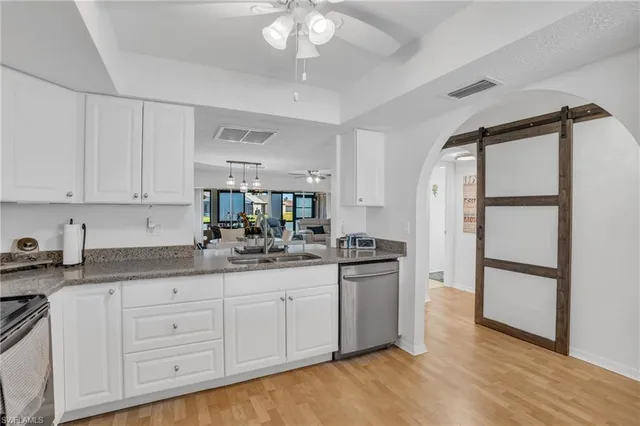 a kitchen with granite countertop a sink cabinets and stainless steel appliances
