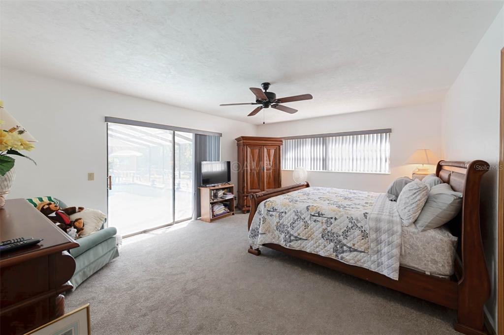 2298 West Pine Ridge Boulevard Beverly Hills, FL 34465 - Photo 19 of 34 a spacious bedroom with a bed and a chandelier