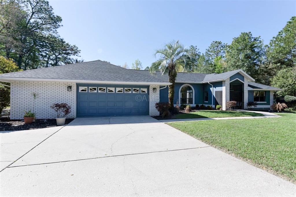 2298 West Pine Ridge Boulevard Beverly Hills, FL 34465 - Photo 2 of 34 a front view of a house with a garden