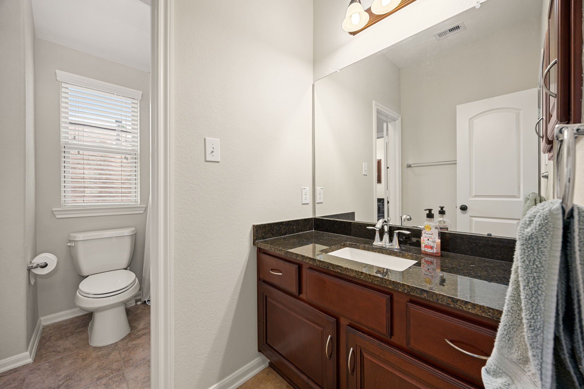 22 South Marshside Place Spring, TX 77389 - Photo 36 of 43 a bathroom with a granite countertop sink a toilet and a mirror