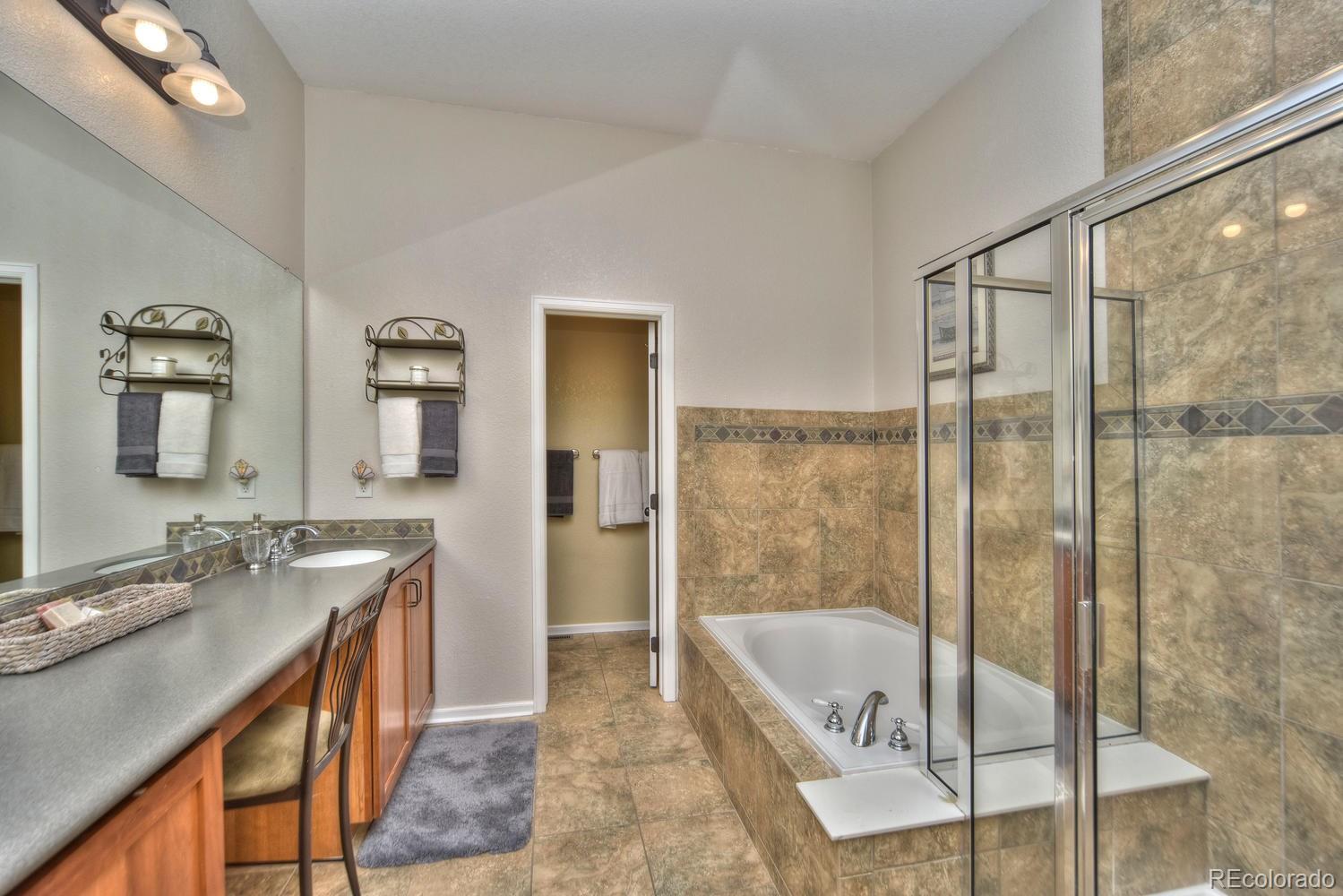 4464 Eagle River Run Broomfield, CO 80023 - Photo 17 of 32 a bathroom with a granite countertop sink a mirror and a bathtub