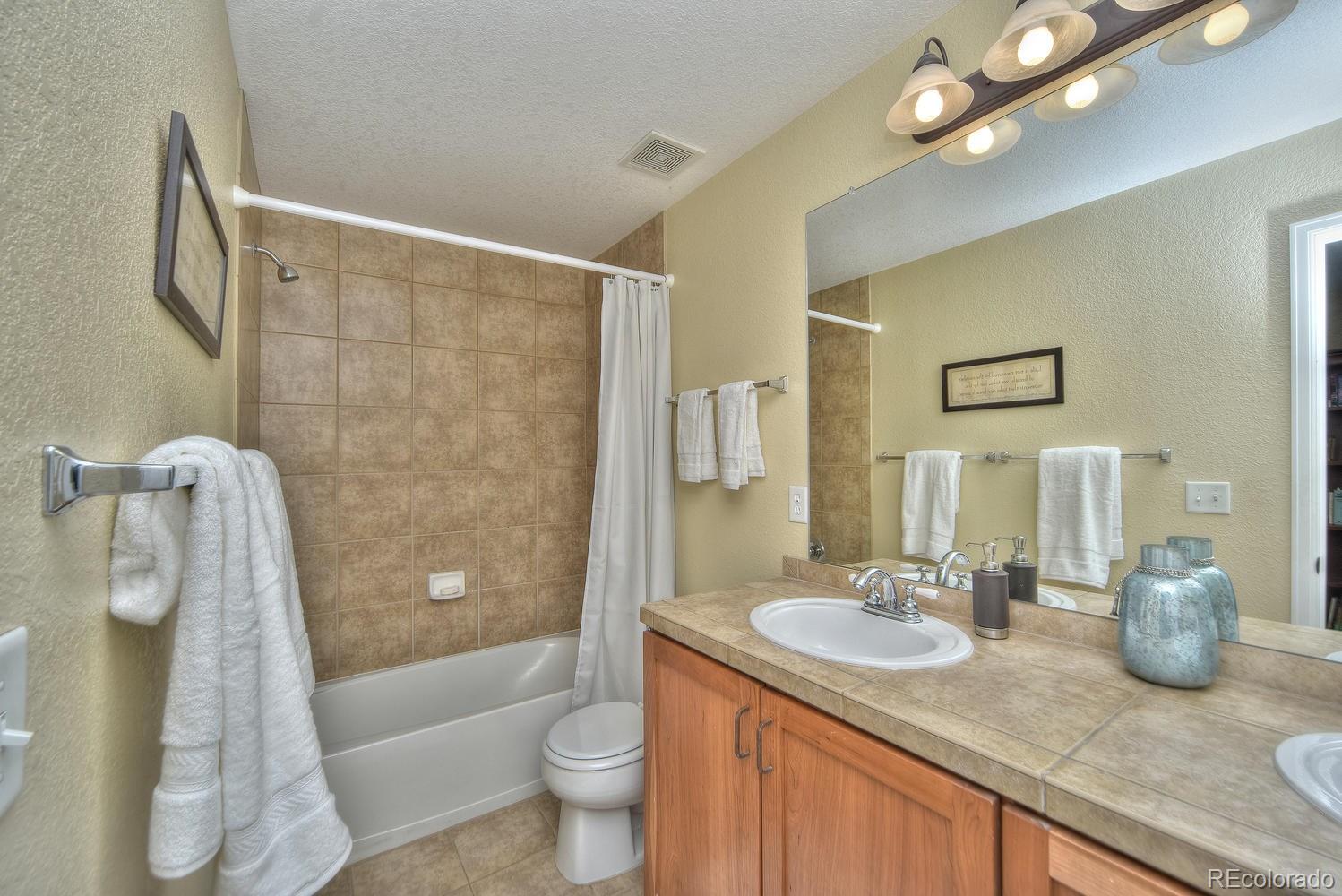 4464 Eagle River Run Broomfield, CO 80023 - Photo 20 of 32 a bathroom with a granite countertop sink a toilet and shower