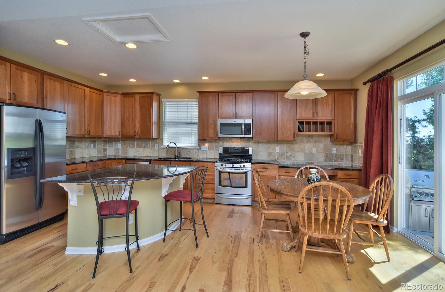 4464 Eagle River Run Broomfield, CO 80023 - Photo 9 of 32 a kitchen with a table chairs refrigerator and cabinets