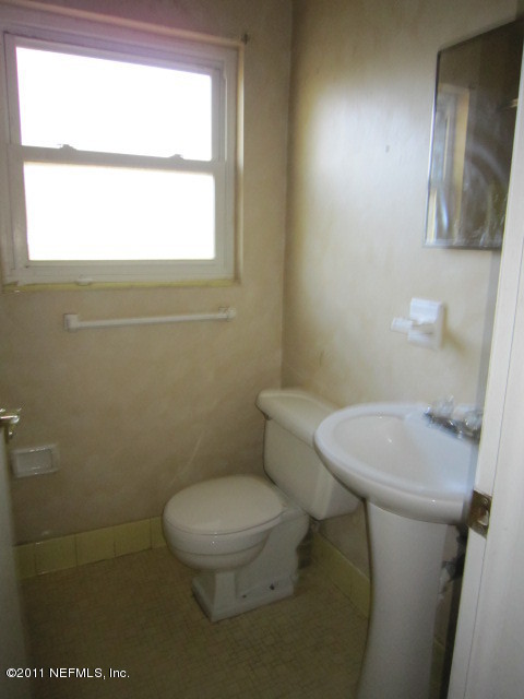 6958 Rollo Road Jacksonville, FL 32205 - Photo 7 of 8 a white toilet sitting next to a window in a bathroom
