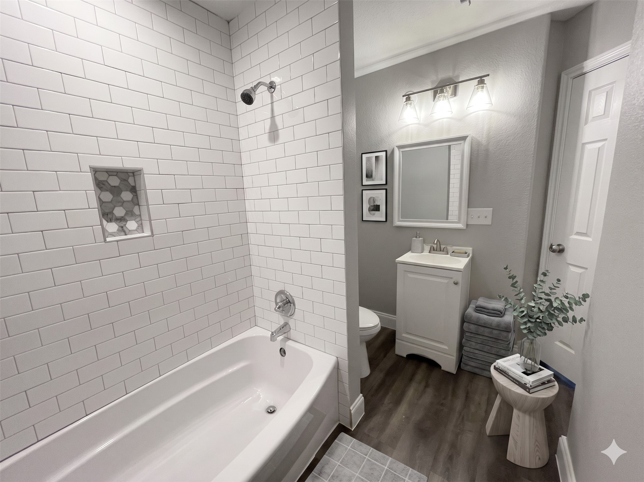 2004 Maple Street Georgetown, TX 78626 - Photo 26 of 31 Bathroom featuring a white subway tile tub surround with integrated niche, chrome shower fixtures, a white vanity with an undermount sink, and wood-finish flooring