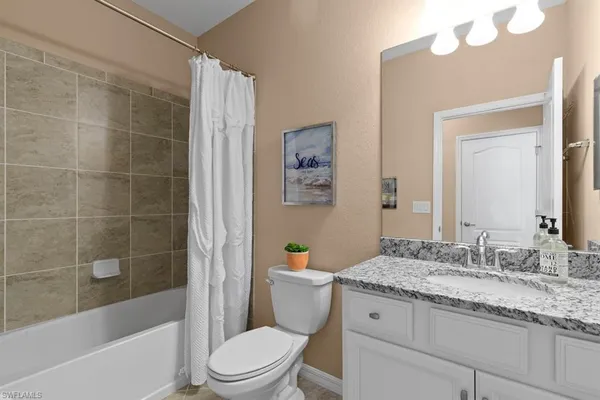 a bathroom with a granite countertop sink a toilet and shower