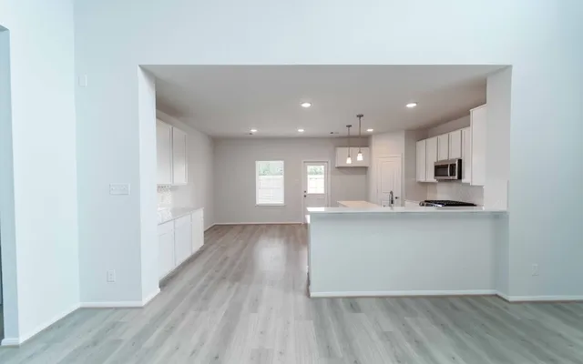 a kitchen with stainless steel appliances granite countertop a refrigerator a sink dishwasher a stove and white countertops with wooden floor