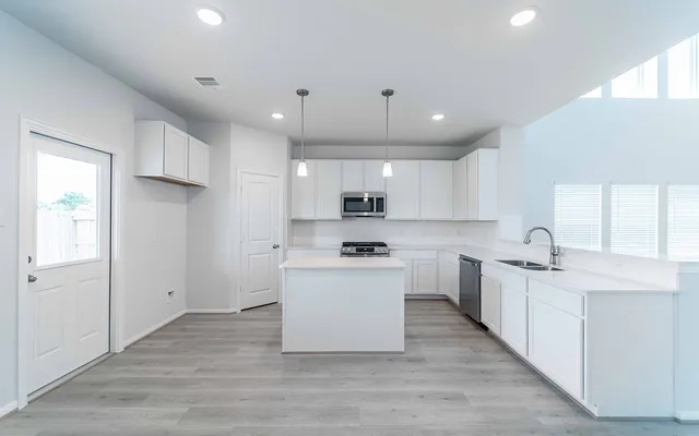 a kitchen with stainless steel appliances kitchen island wooden floors white cabinets and window