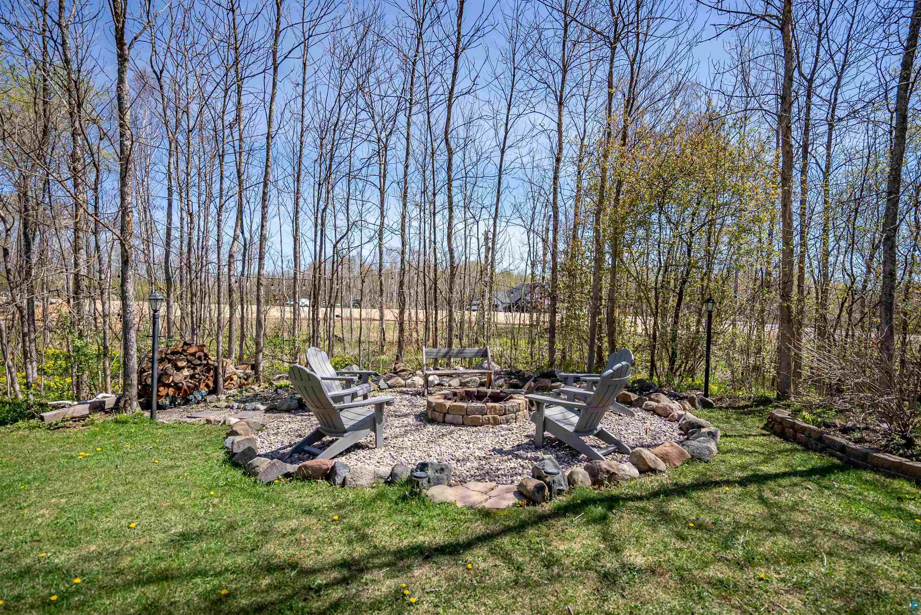 4809 Oak Ridge Drive Hermantown, MN 55811 - Photo 49 of 69 Outdoor fire pit area with a stone and gravel surround, featuring a manicured lawn