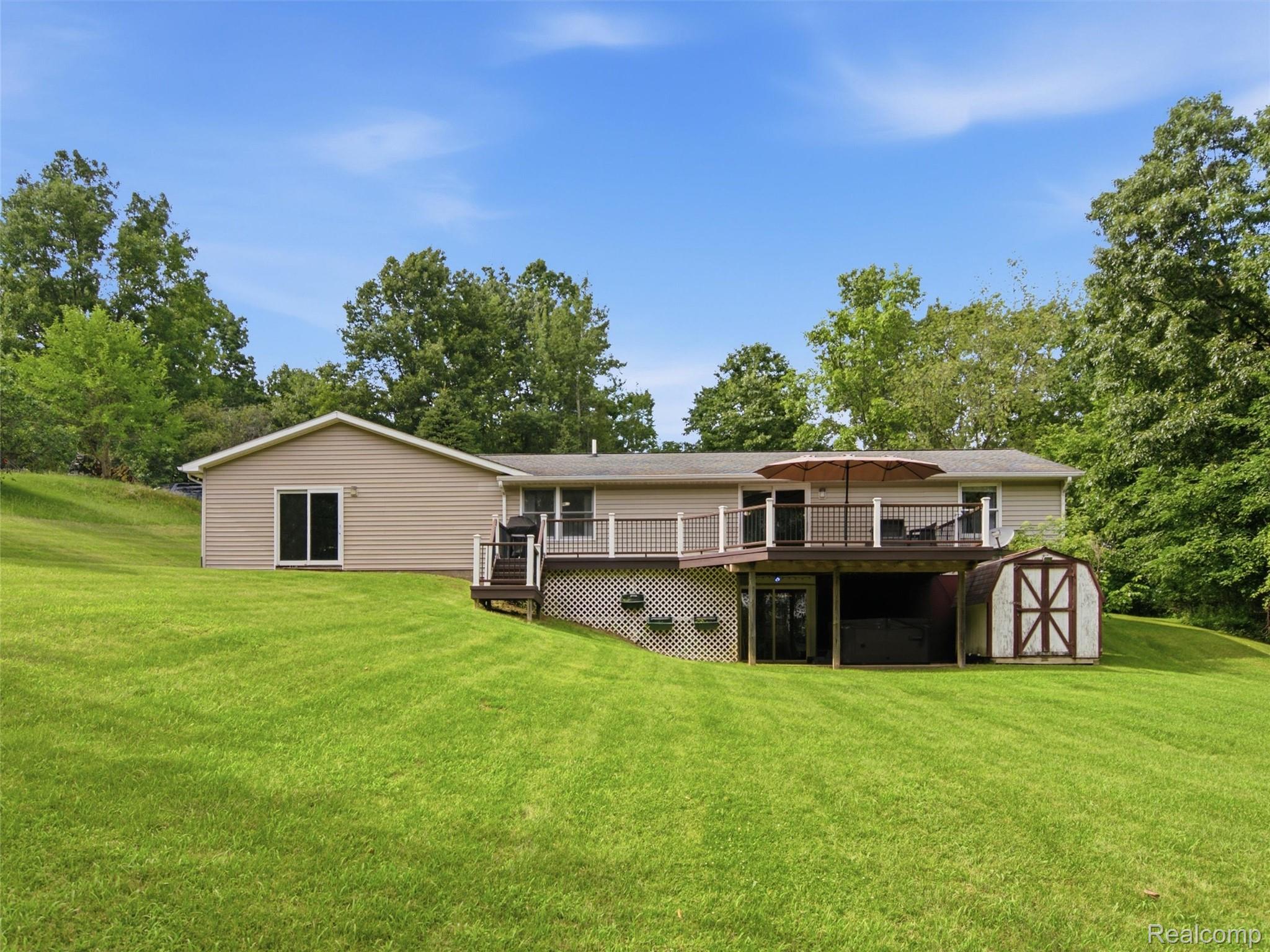 5003 Mason Road Howell, MI 48843 - Photo 39 of 59 Rear exterior featuring a multi-level deck with dark railing, tan horizontal siding, and a gabled roofline