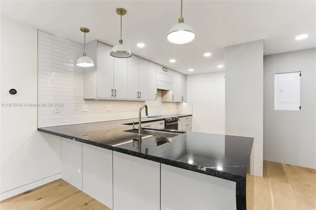 a kitchen with kitchen island granite countertop a sink a counter space appliances and cabinets