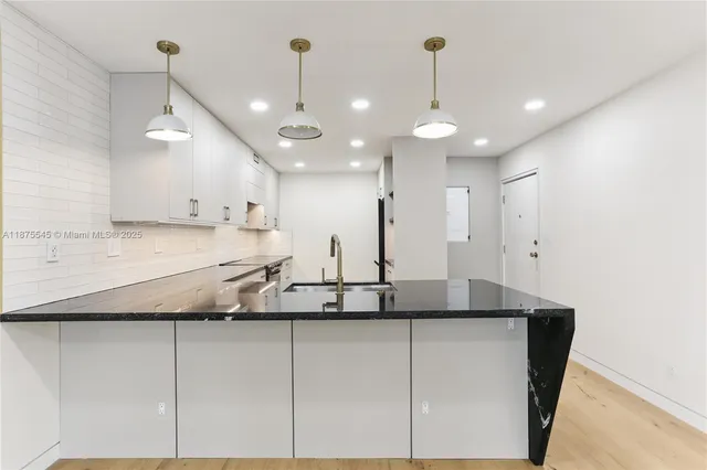 a large kitchen with stainless steel appliances kitchen island granite countertop a stove a sink a refrigerator and white cabinets