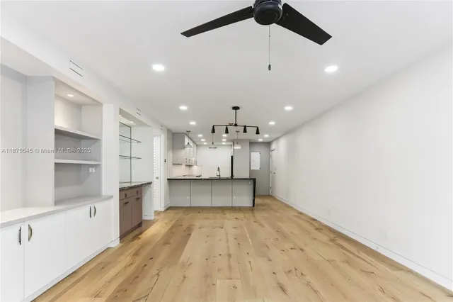 a large kitchen with kitchen island a stove a sink a refrigerator and white cabinets with wooden floor