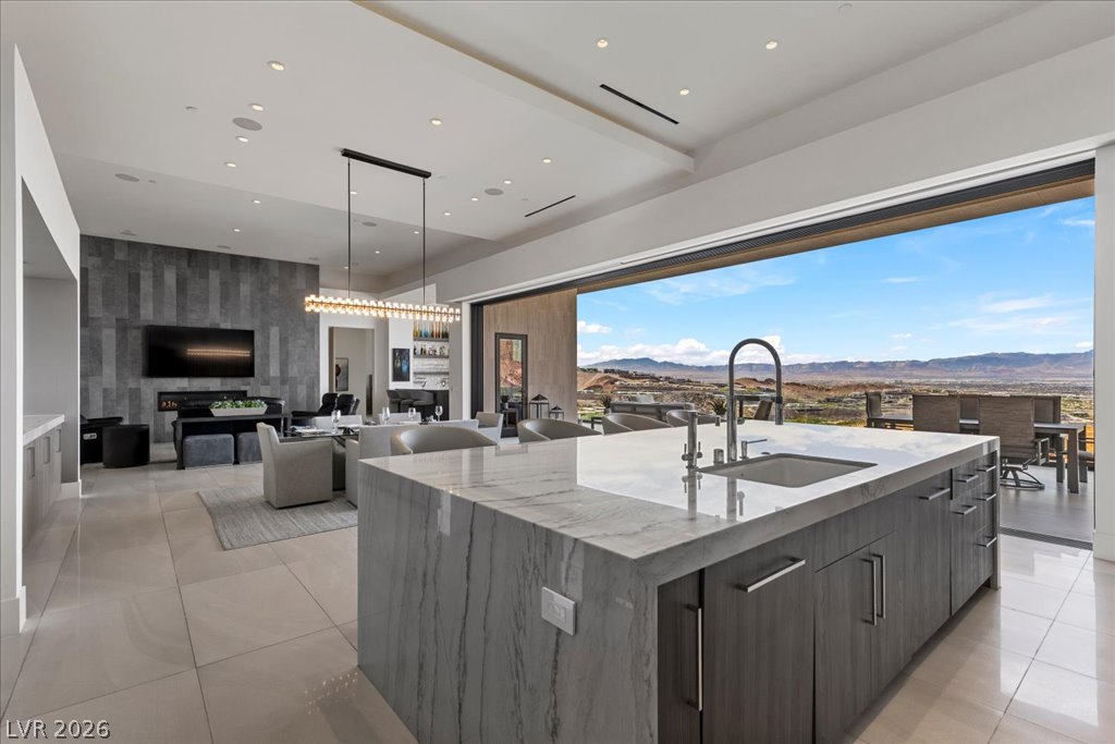 657 Ridgestone Rim Court Henderson, NV 89012 - Photo 11 of 97 Retractable glass doors frame distant mountain views from this contemporary open-plan kitchen and living space.