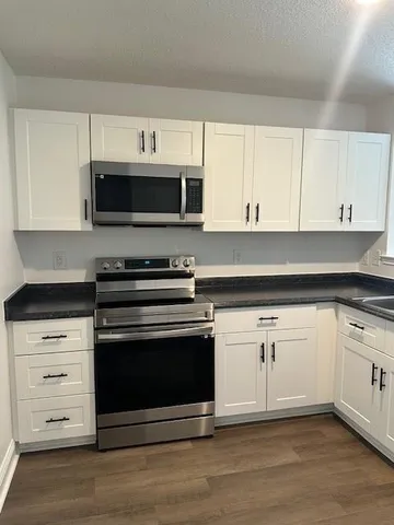 a kitchen with stainless steel appliances granite countertop a stove microwave and cabinets