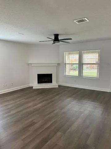 an empty room with wooden floor fireplace and windows