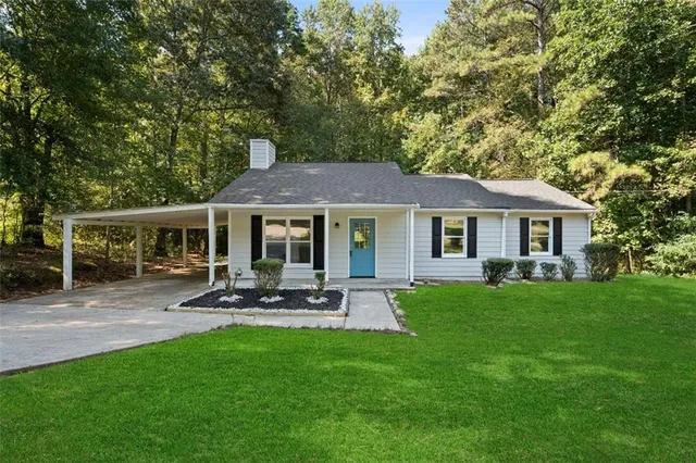 a front view of a house with garden and trees